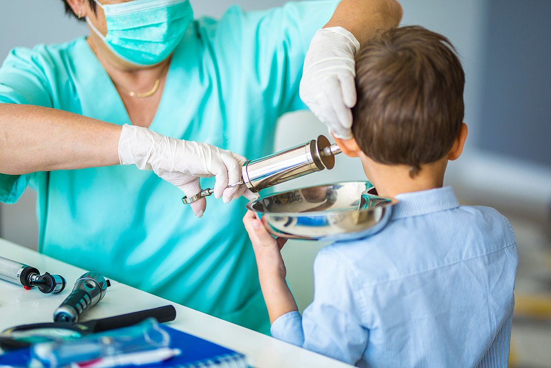 Infermiere che esegue la rimozione di un tappo di cerume tramite lavaggio auricolare professionale